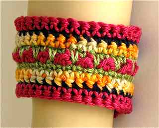 Close up of the single crochet stitch color changes and center accent aran stitch texture of bracelet cuff.