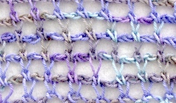 Tunisian crochet extended stitch in a simple net pattern with hand dyed sock yarn in light purples, tans, and sea blues.