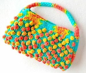 One ball of hand painted yarn, its colors intentionally "pooled" into two stitch patterns (popcorns and seed/moss/linen st) to create this "Florida Peaches Handbag"