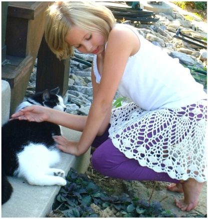 Tween-aged girl wears an "exploded doily" style skirt by Doris Chan as she pets a cat.