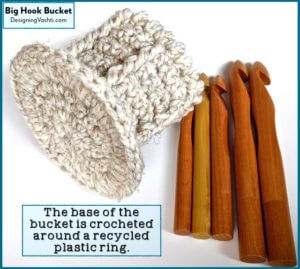 Set of 5 sizes of jumbo wood crochet hooks, and the crocheted "bucket" caddy for them showing the base that's reinforced by crocheting around a recycled plastic ring.