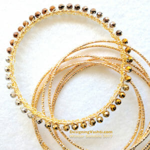 A slim gold bangle is covered with gold wire crochet and metal beads.