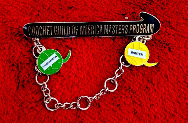 The new CGOA Master's Program pin. I've earned two charms so far: Writer, and Fundamentals (because I wrote a few chapters of it).