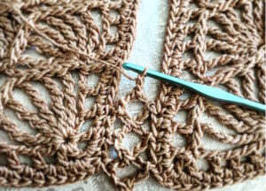 Close up of seam that joins two crochet motifs with stitch equivalents: linked bent tall stitches match chains and slip stitches.
