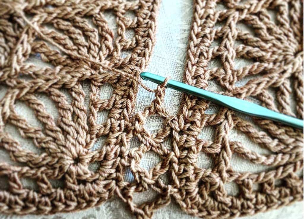 Close up of seam that joins two crochet motifs with stitch equivalents: linked bent tall stitches match chains and slip stitches.