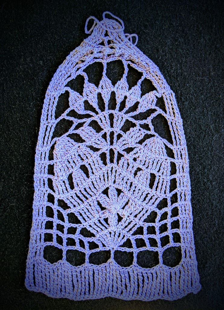 Arch-shaped swatch of a framed folk-style heart with a flower at the center, all in very tall crochet stitch combinations.