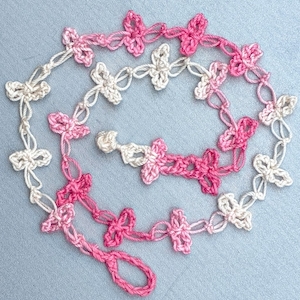 Crochet mask chain of lacy pink love knots and crocheted fasteners.