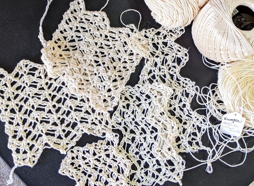 Pile of lacy cream-colored antique-looking Tunisian crochet swatches